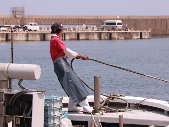 一人の女性が船を港につけるため、ロープを引っ張っているところの写真