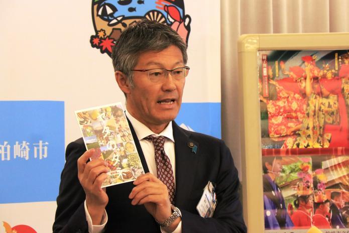 インターン生が作成した冊子「ヤタのタネ」を手に持ち話している櫻井市長の写真
