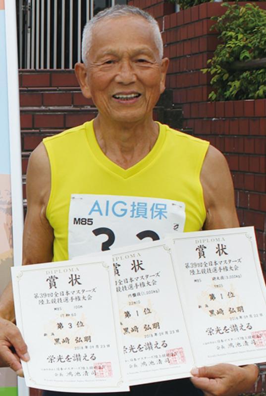 黄色いユニフォームを着て、3枚の賞状を持つ黒崎さんの写真