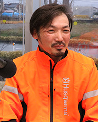 蛍光オレンジの森林ウエアを着た従業員の中村貴洋さん