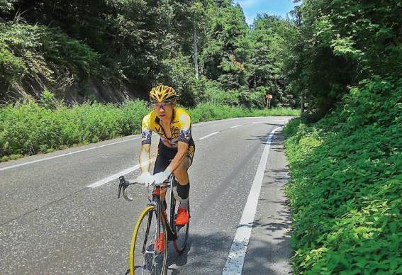 レース用の自転車に乗り、坂道を上る村山さんの写真
