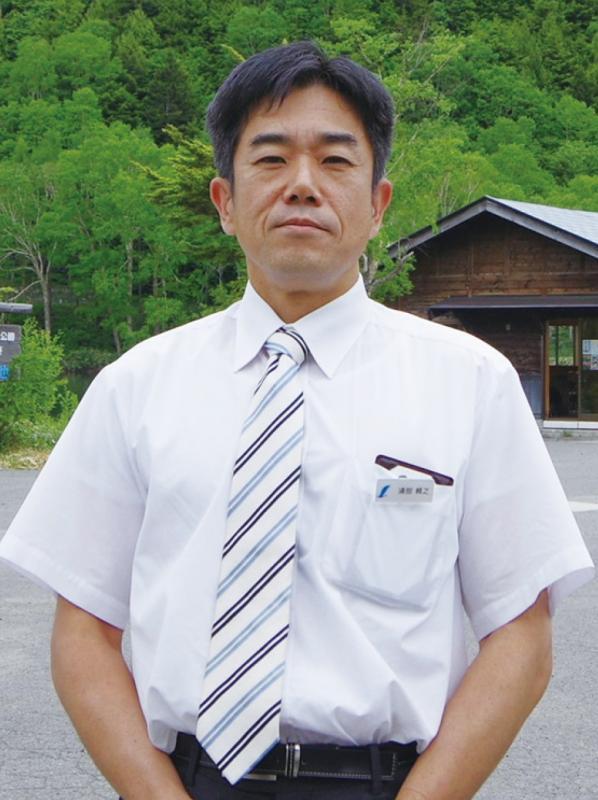 ワイシャツにななめストライプのネクタイをしている浦部さんの写真