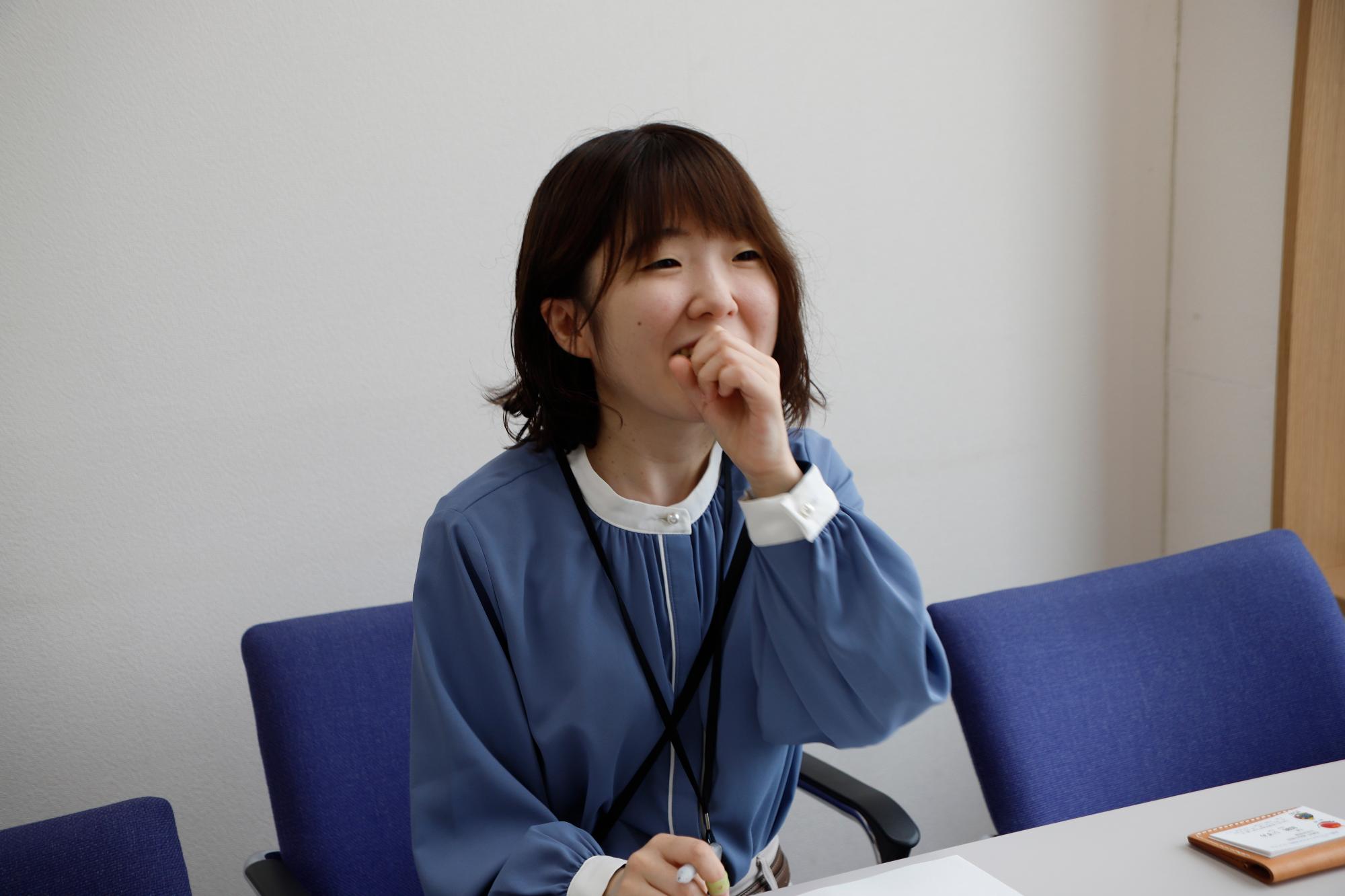 写真：口元に手を当てインタビューに答える尾崎さん