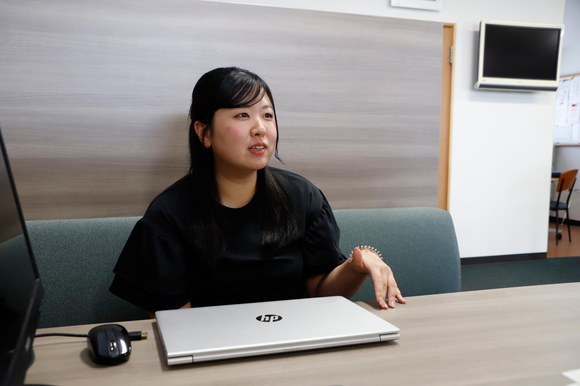 写真：会社の打ち合わせスペースでインタビューに答える田川さん