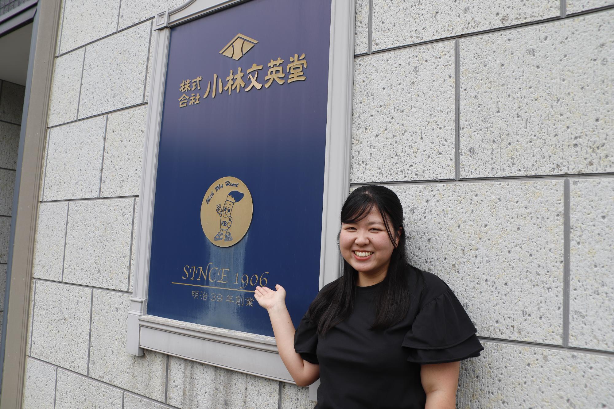 写真：小林文英堂の伝統的な看板前に立つ田川さん