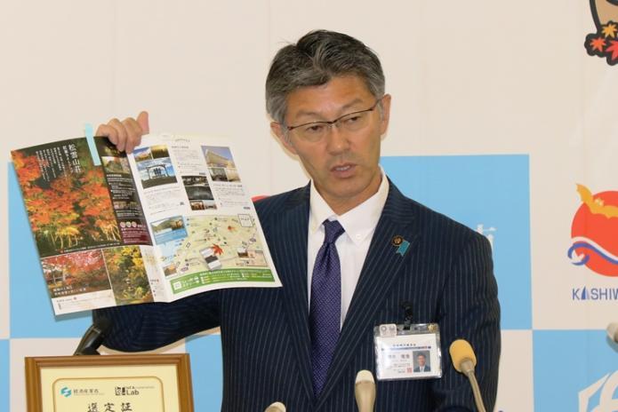 観光パンフレットを広げながら説明をする市長の写真