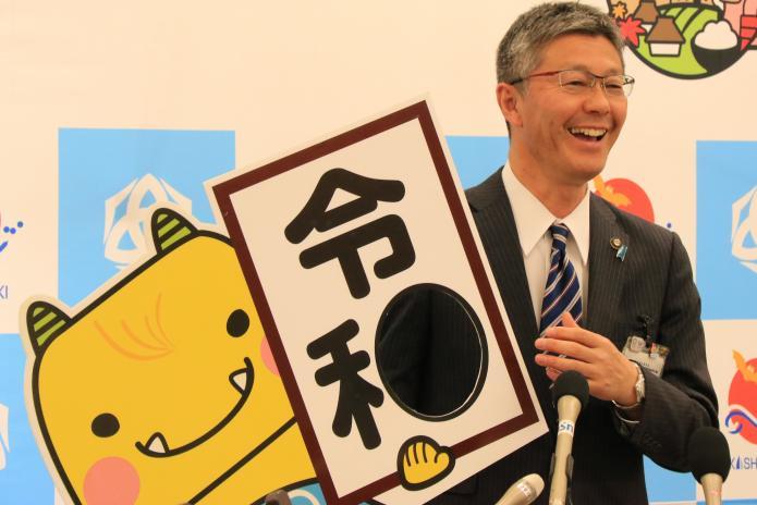 5月市長記者会見で「令和」とえちごんが書かれたボードを笑顔で持っている市長の写真